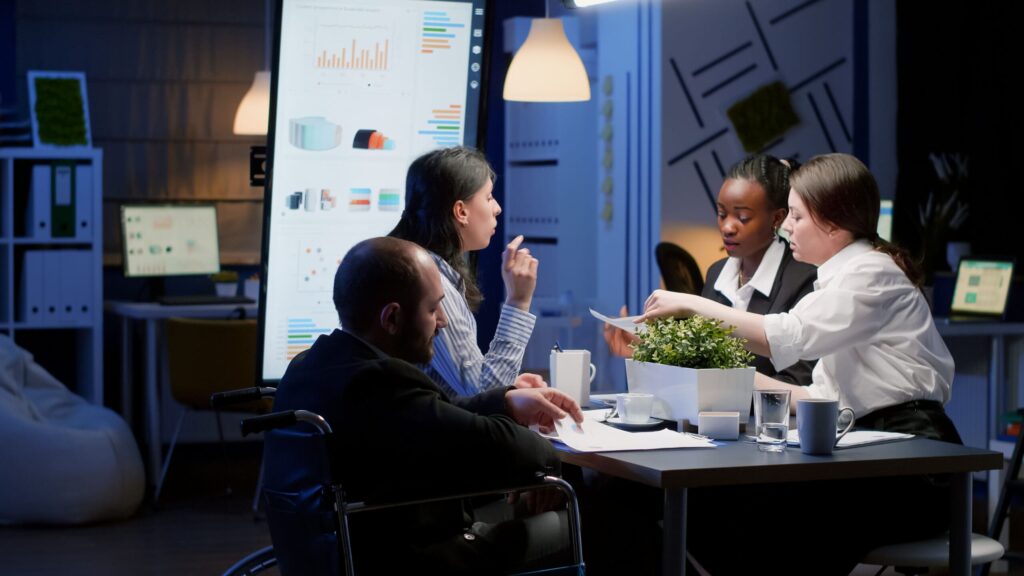 Handicapped paralyzed manager man in wheelchair sitting at conference table-img